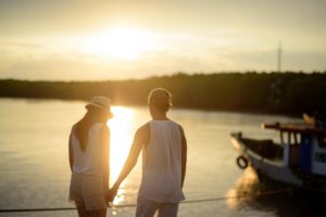 Pareja joven cogida de la mano en un atardecer