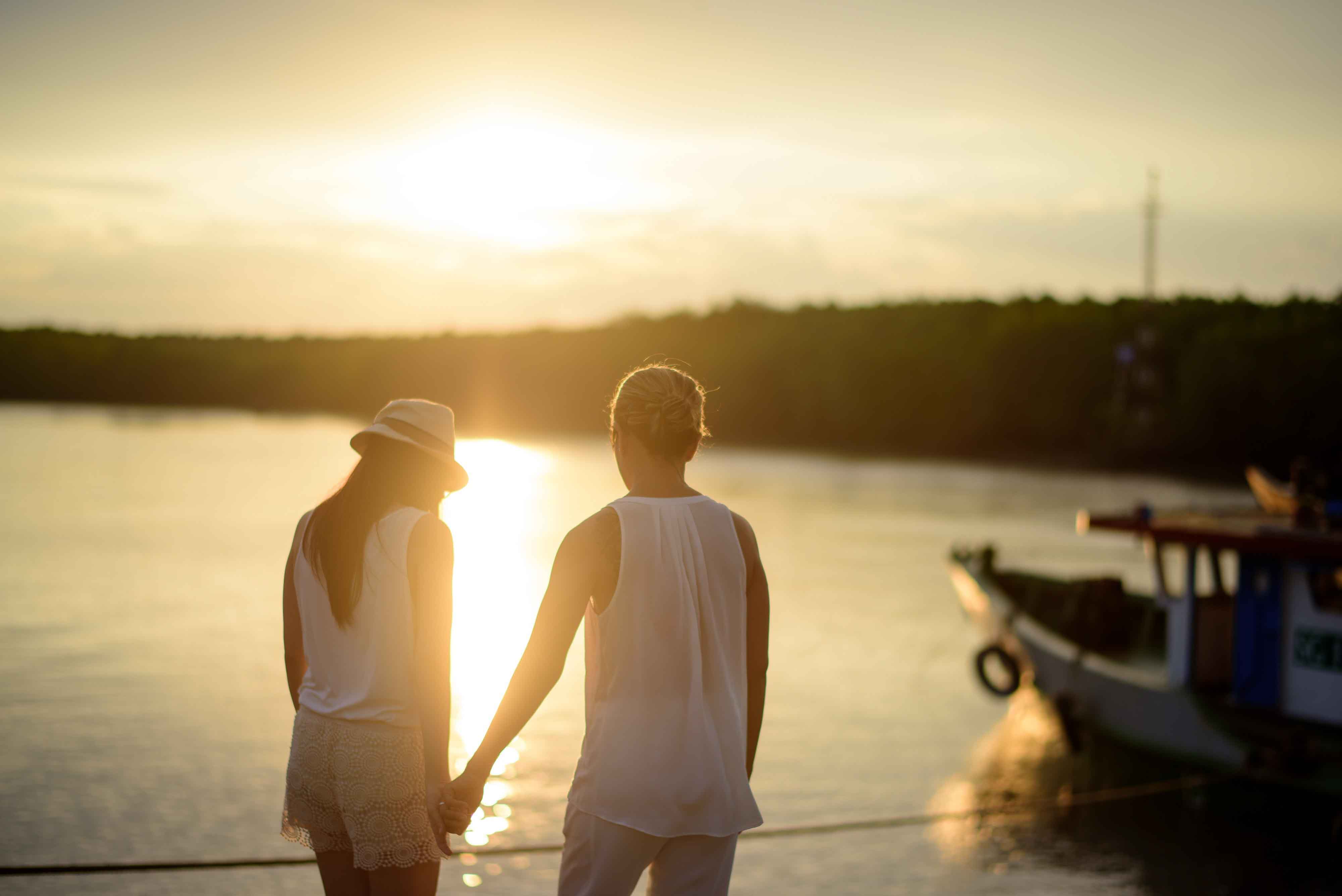 Pareja joven cogida de la mano en un atardecer
