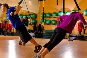 Gente entrenando con cintas TRX en gimnasio